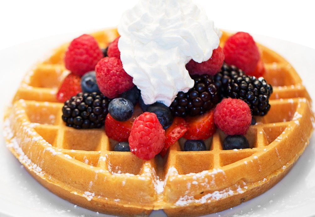 Waffle topped with fresh berries and whipped cream