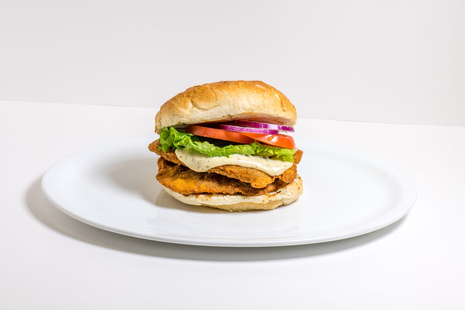 Crispy chicken burger with lettuce, tomato and red onion